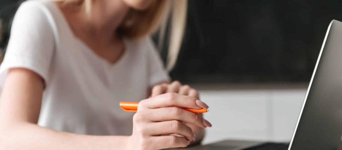 Cropped photo of young blonde concentrated businesswoman working with laptop at home